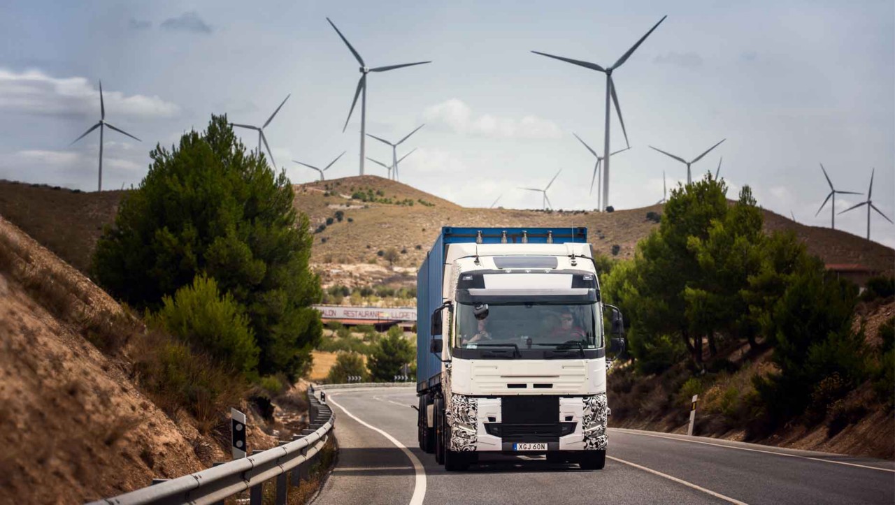 Zkušební vozidlo na silnici ve Španělsku s větrnými elektrárnami v pozadí